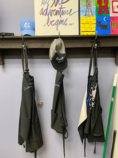 Barber aprons and caps hanging on hooks inside the shop