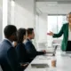 Native American female CEO confidently leading a strategic boardroom discussion with colleagues regarding the benefits of WOSB certification for federal contracting.