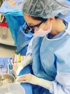 Double board-certified facial plastic surgeon Dr. Susan Tan performing a precise procedure in a sterile Honolulu operating room.