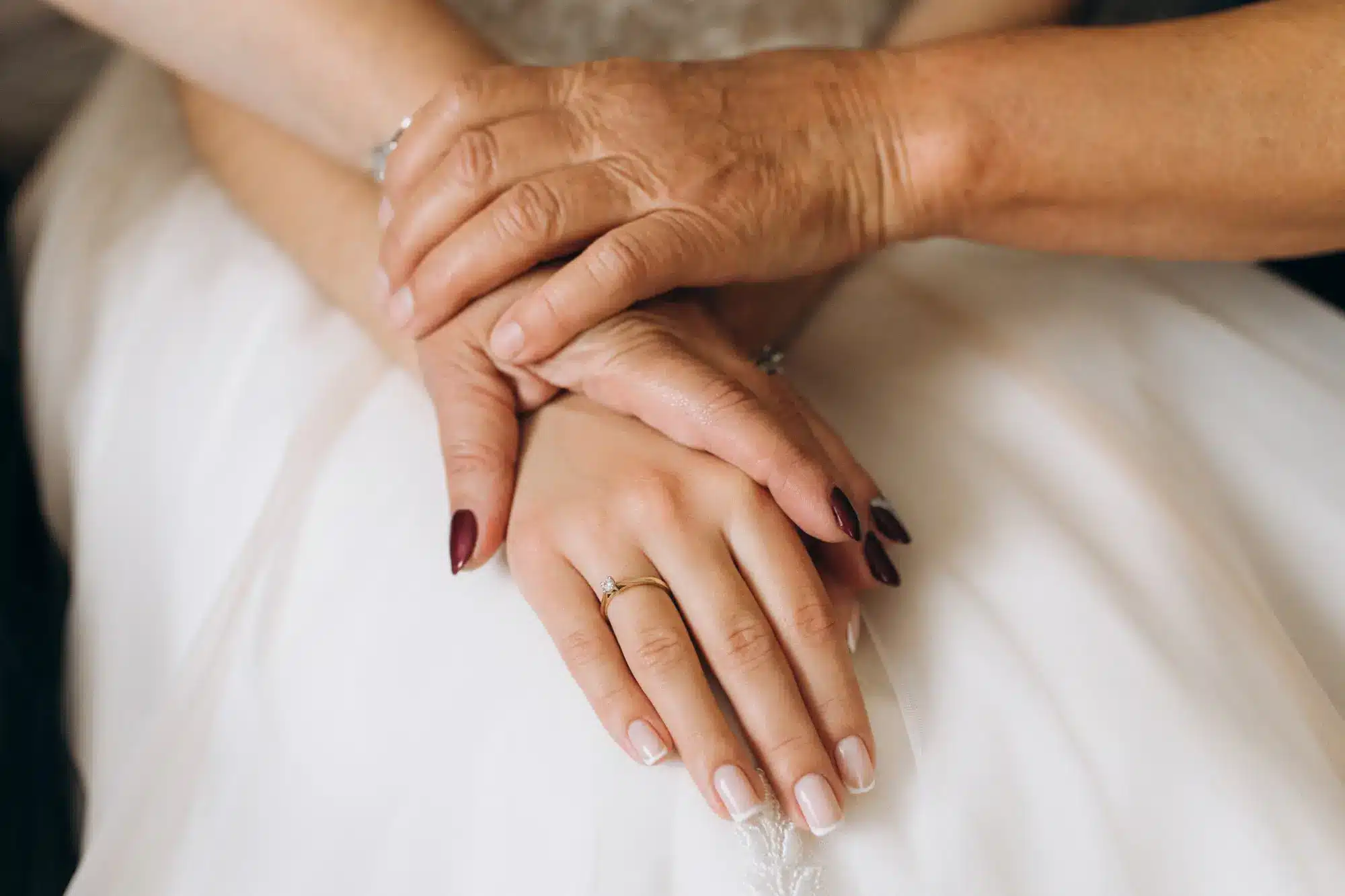 A close-up of aged hands resting over smooth, youthful hands with a diamond ring, visualizing the ultimate goal of hand rejuvenation results.