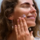 Woman applying sunscreen on a Hawaii beach, protecting her face after surgery with Dr Susan Tan at Hawaii Facial Plastic Surgery.